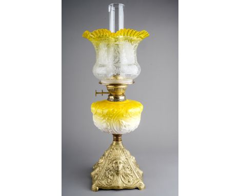 A Victorian style gilt metal oil lamp, the yellow resevoir moulded with scrolling flowers, with etched shade with frilly yell