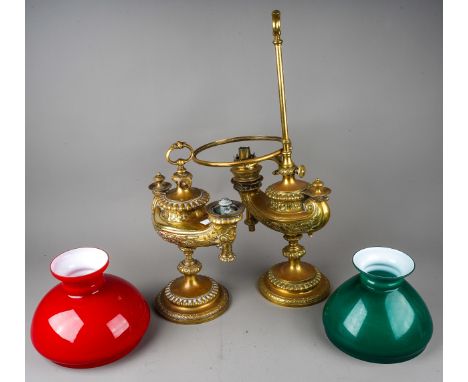 A matched pair of German Wild & Wessel 1373 Aladdin style brass table lamps, with red over white glass shade and a green over