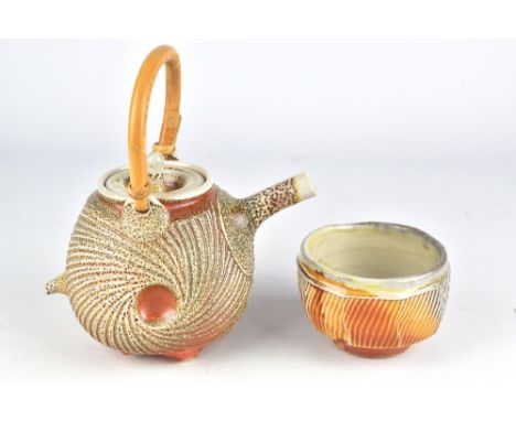 JAMIE KIRKPATRICK; a soda fired&nbsp;porcelaneous stoneware teapot with carved surface and cane handle and a matching cup, im