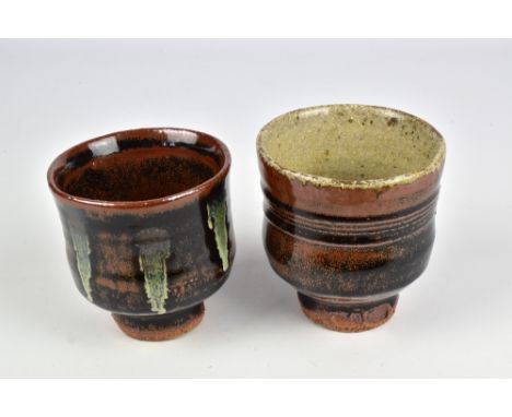 JIM MALONE (born 1946); a stoneware yunomi covered in ash and tenmoku breaking to kaki glaze and another example with copper 