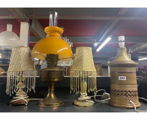 A 1970's stoneware lamp base, two onyx table lamps and a brass oil lamp.