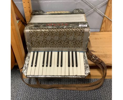 A vintage Alvari piano accordion with a case of sheet music.
