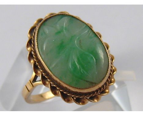 A 9 carat gold carved jade ring, jade approx 15 x 10mm, ring size M, 2.8 gms.
