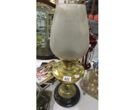 A brass oil lamp on black pottery base and with frosted glass shade
