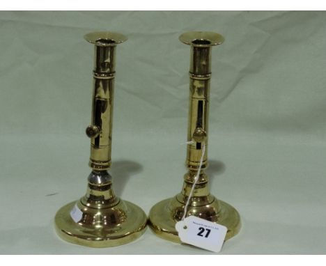A Pair Of Circular Based Antique Brass Candle Holders With Side Push Button Action