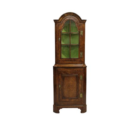 A Queen Anne style walnut glazed corner cupboard the arched pediment over a six paned single door opening to shelving, the ba