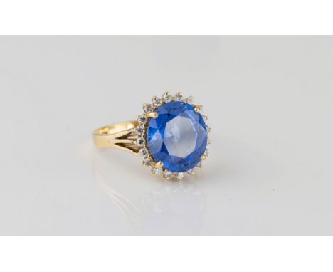 An 18ct yellow gold, sapphire and diamond cluster ring the cornflower blue, oval cut sapphire measuring 12 x 10.5mm., approx.