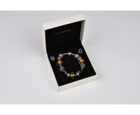 A Pandora bracelet with eleven silver charms in silver, black and amber tones, most set with crystals or glass, plus two furt