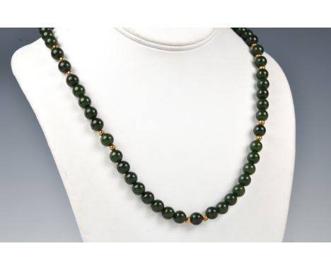 A dark spinach jade bead and 18ct gold necklace the evenly sized 7mm. jade beads interspersed with small 18ct gold beads, wit