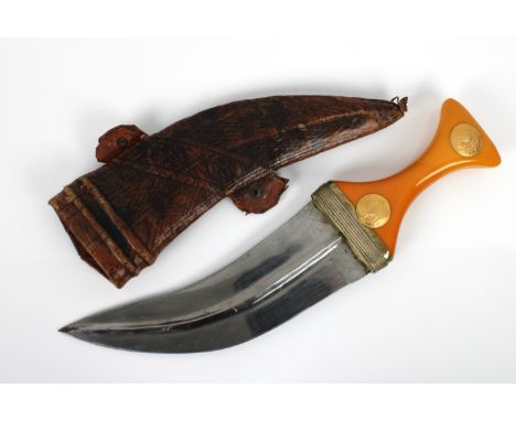 A Middle Eastern Jambiya dagger with yellow metal mounted amber colour bakelite handle, characteristic curved blade, original