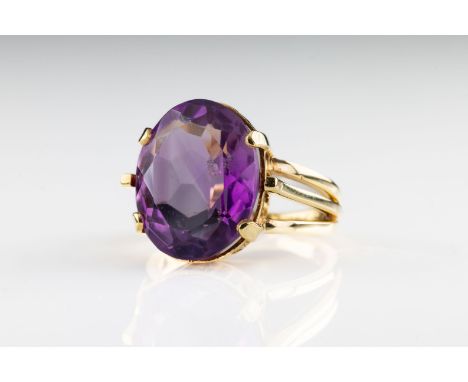 An amethyst cocktail ring The oval shaped amethyst claw set in a 14ct yellow gold band with split shoulders, rings size L 1/2