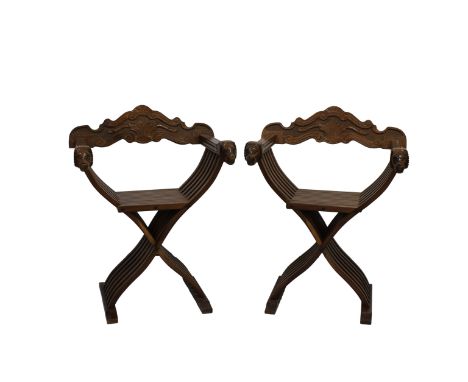 A Pair of Savonarola chairs 20th century, the foliate and scroll carved removable backs over carved arms terminating in lions