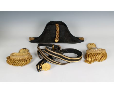 An Edwardian full dress Royal Navy bicorn cocked hat, pair of epaulettes and sword belt in a fitted red velvet lined metal tr