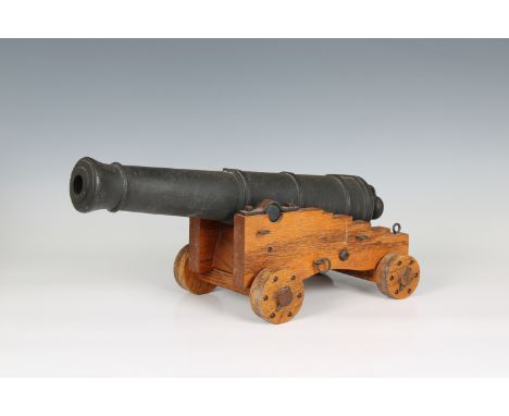 A model cannon with an iron barrel and wooden stepped four wheeled gun carriage barrel 15¾in (40cm.) long, 3 3/8in. (8.6cm.) 
