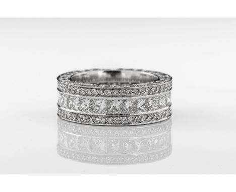 A diamond three row eternity ring The 18ct white gold ring set with a central band of princess-cut diamonds with a row of bri