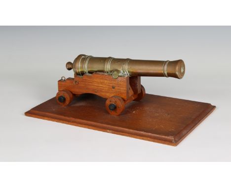 A model cannon with a polished brass barrel and wooden stepped four wheeled gun carriage barrel 9½in (24.1cm.) long, bore ½in