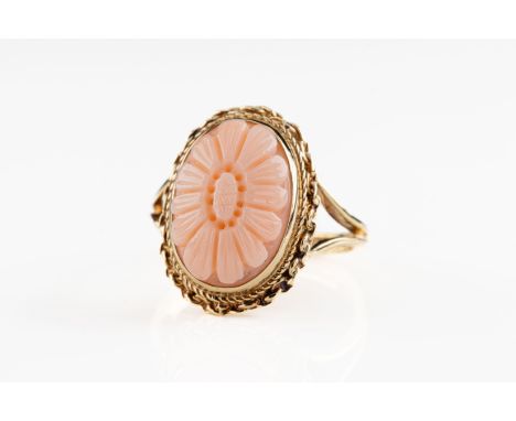 A 9ct yellow gold and coral ring The coral carved in floral daisy design, within a decorative setting with rope twist design 