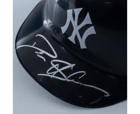 A navy blue Yankees baseball helmet with a white logo, autographed by Deion Sanders in silver ink. American Baseball Company 
