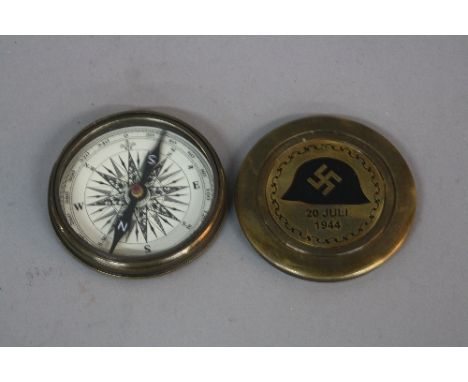 A BRASS ROUND WWII ERA GERMAN COMPASS, with screw top lid, bearing a scrolled circular design, a black enamelled German helme