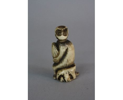 A JAPANESE IVORY NETSUKE OF A SEATED MONKEY HOLDING A GOURD, bears label 'Ex & Collectis T.L. Elliott', height approximately 