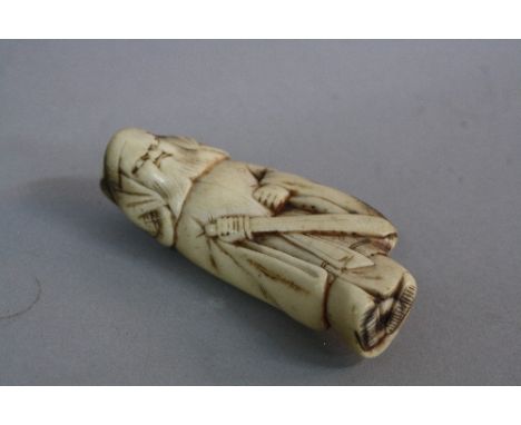 A JAPANESE IVORY NETSUKE OF A MAN WITH A SWORD IN HIS RIGHT HAND, bears label 'Ex Collectis T.L. Elliott', height approximate