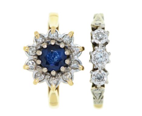 A sapphire and diamond cluster ring and a three stone diamond ring,&nbsp;in 18ct gold, Birmingham, date letter rubbed, or in 