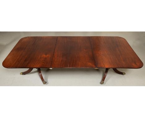 A George IV twin-pillar mahogany dining table, the finely figured top and leaf on baluster pillars and three hipped, leaf car