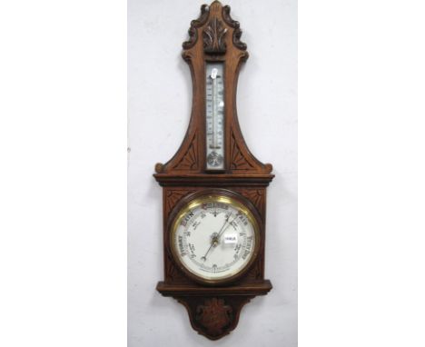 An Early XX Century Oak Cased Aneroid Barometer/Thermometer, with carved and incised decoration in the form of sunburst, foli