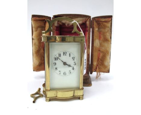An Early XX Century Brass Carriage Clock, of fluted rectangular form, the cream enamel dial with black Arabic numerals, leath