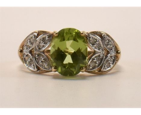 A hallmarked 9ct gold peridot and diamond dress ring. The ring set with an oval mixed cut peridot and round cut diamonds set 