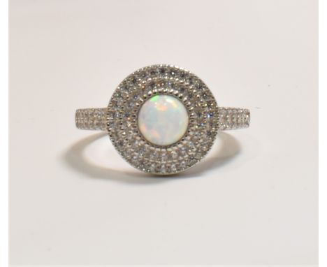 A silver, synthetic opal and cz Art Deco style dress ring. The target ring set with a central round synthetic opal cabochon w