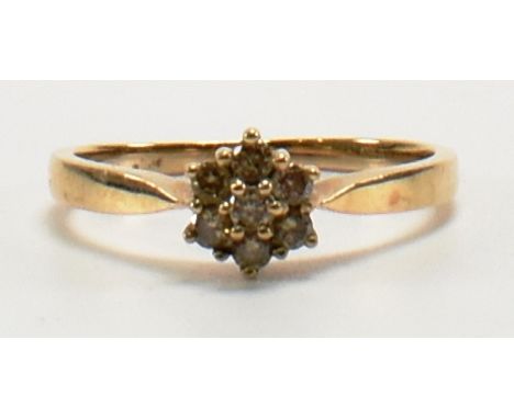 A hallmarked 9ct gold and diamond cluster ring. The ring set with seven champagne diamonds in a cluster setting to plain tape