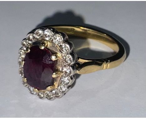 An 18ct gold, diamond and ruby ring, stamped '18ct' for 18ct gold, the central facet cut oval stone claw set above a ring or 