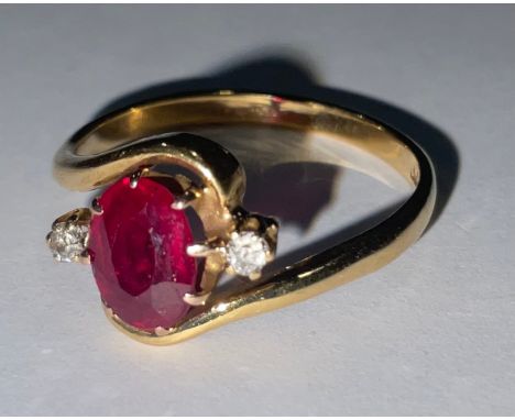 A ruby and diamond three stone 18ct gold ring, the central oval cut ruby flanked by two old brilliant cut diamonds, size L/M 