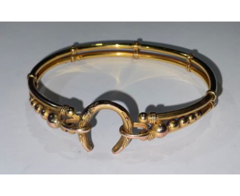 A gold coloured metal hollow cast bangle, the clasp as a horse shoe, approximately 7g 
