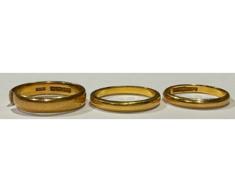 A 22ct gold "Lucky Star" wedding band, size K, 2.7g; a 22ct gold wedding band, size M/N, Birmingham 1954, 3.6g; a 22ct gold w