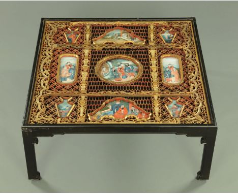 A Chinese low table, with fretwork and reverse painted glass panels, ebonised frame and raised on four shaped legs.  Top 102 