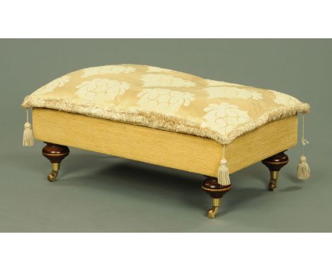An upholstered stool, originally supplied by Harrods, with loose cushion and raised on four turned legs on brass castors.  Ba