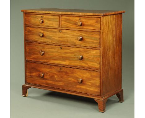 An early 19th century mahogany chest of drawers, with two short and three long drawers with wooden knob handles and cockbeadi