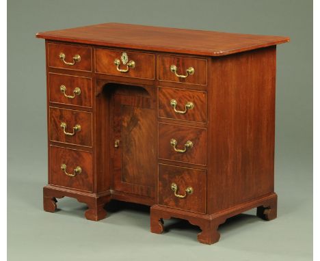 A 19th century mahogany kneehole desk, with moulded edge above a series of drawers and recessed cupboard with brass drop hand