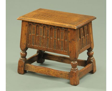 An oak stool, with hinged top to open interior and with knulled and carved frieze and raised on angled legs united by stretch