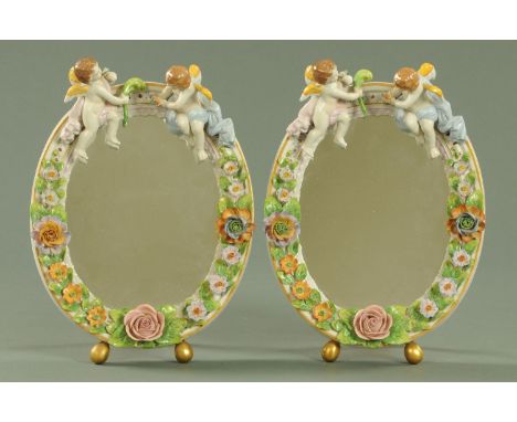 A pair of Sitzendorf attributed porcelain dressing table mirrors, 20th century, each mounted with two cherubs with either pin