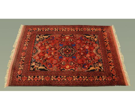 A large Persian design woollen fringed rug, with centre rectangular panel decorated with vases, jugs and bowls and with repea
