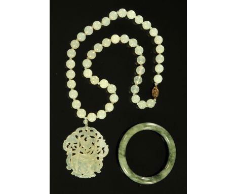 A Chinese jade pendant on beaded necklace, 20th century, with silver gilt clasp, the pendant with fretwork decoration of a fl