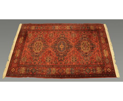 A Belgian wool Persian design fringed carpet, with centre rectangular panel and three line border decorated in red, black and