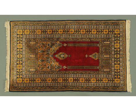 An Eastern prayer rug, silky pile, with fringed ends, with centre rectangular panel with pillars and red ground and with mult