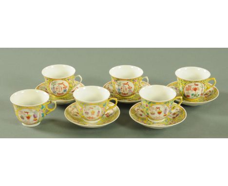 A set of six Chinese porcelain tea cups and saucers, early 20th century, with panels of precious objects against a yellow gro