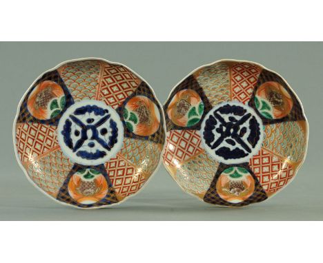 A pair of Japanese dished plates, circa 1880, each with stylised underglazed blue centre framed by fan shaped panels of diape