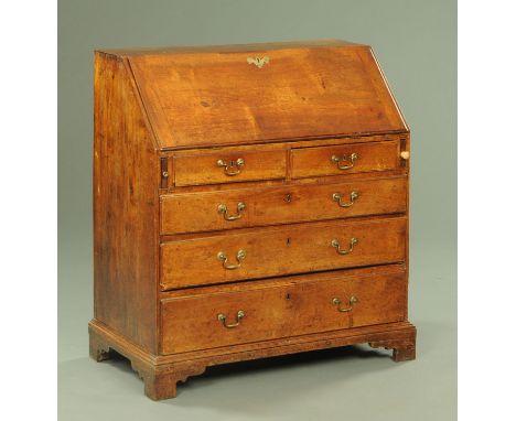 A George III bureau, with slope font to fitted interior above two short and three long drawers with brass drop handles and ra