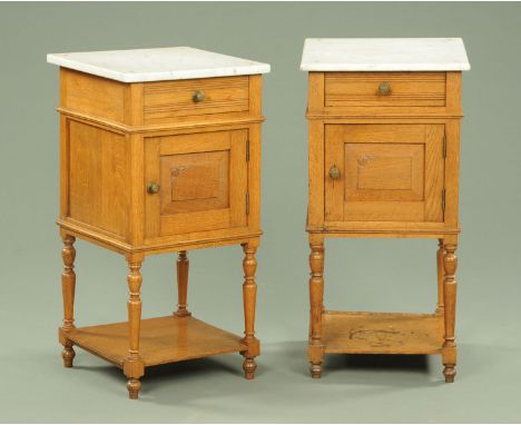 A pair of Edwardian oak bedside cabinets, each with marble top above a drawer and cupboard and raised on turned legs with low